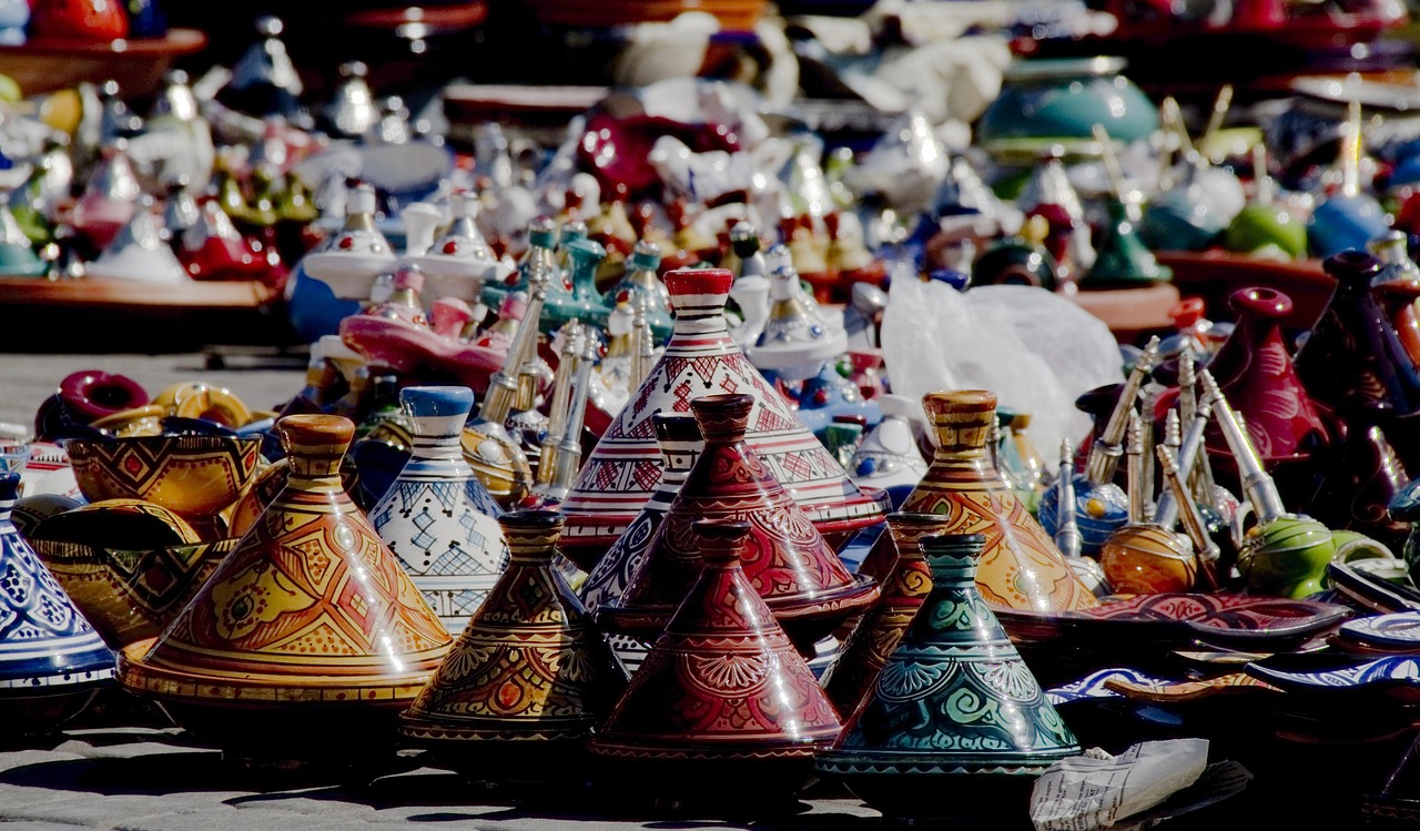 Mercato di Marrakech con bancarelle colorate e vivaci, artisti locali e turisti immersi nell'atmosfera.