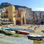 Vista panoramica di Cefalù con la cattedrale e il lungomare affacciato sul mare.