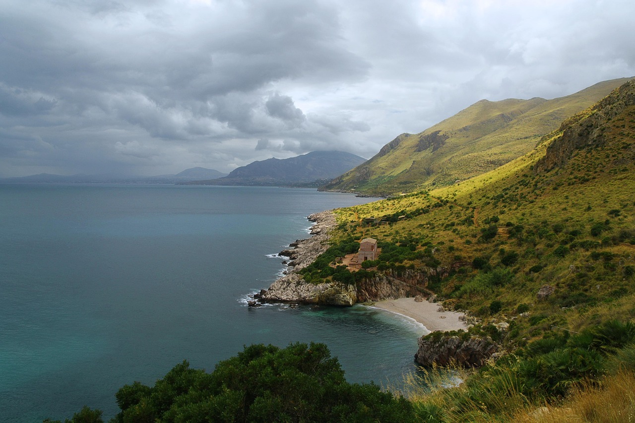 Una spiaggia nascosta in Sicilia con acque cristalline e sabbia dorata, circondata da scogliere.