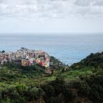 Panorama mozzafiato del villaggio ligure sul mare, con case colorate e cielo azzurro.