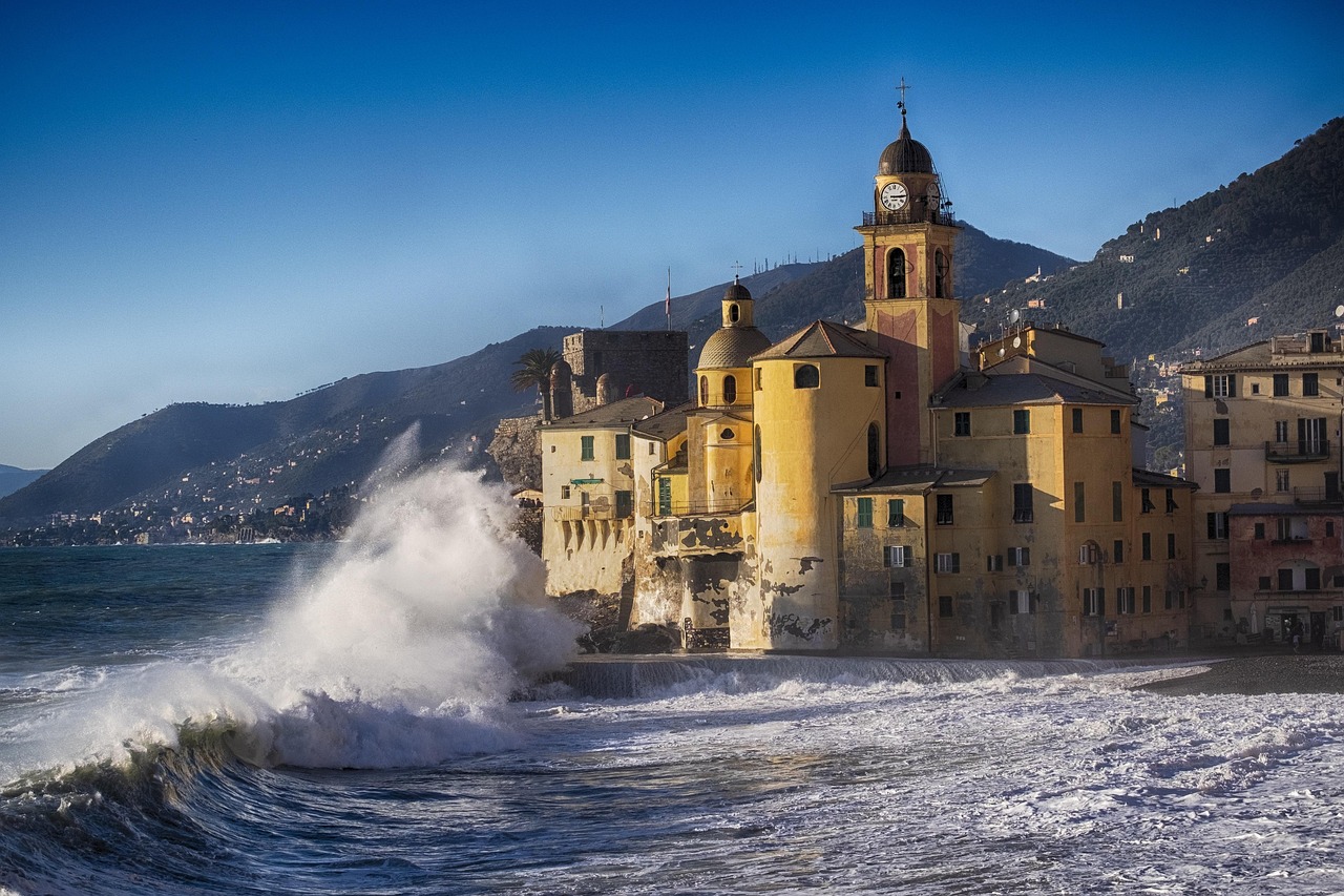 Panorama di un caratteristico paesino ligure affacciato sul mare, con case colorate e un cielo azzurro.