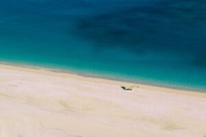 Spiaggia segreta in Albania con sabbia dorata e acque cristalline, circondata da natura incontaminata.