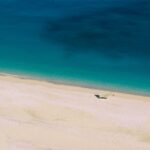 Spiaggia incontaminata in Albania con acque turchesi e sabbia dorata, circondata da natura rigogliosa.