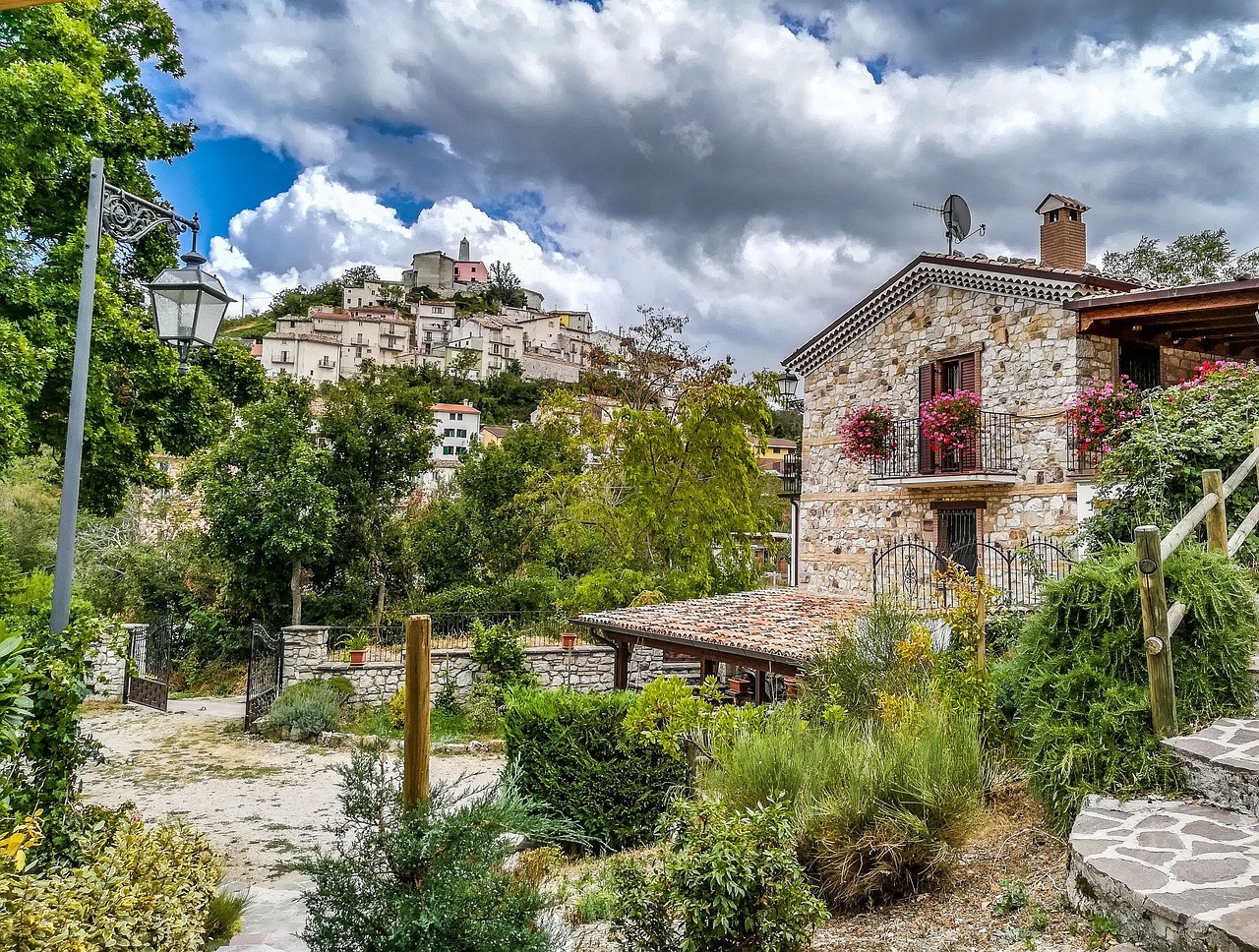 Borgo abruzzese immerso nella natura, con montagne verdi e case in pietra tradizionali.