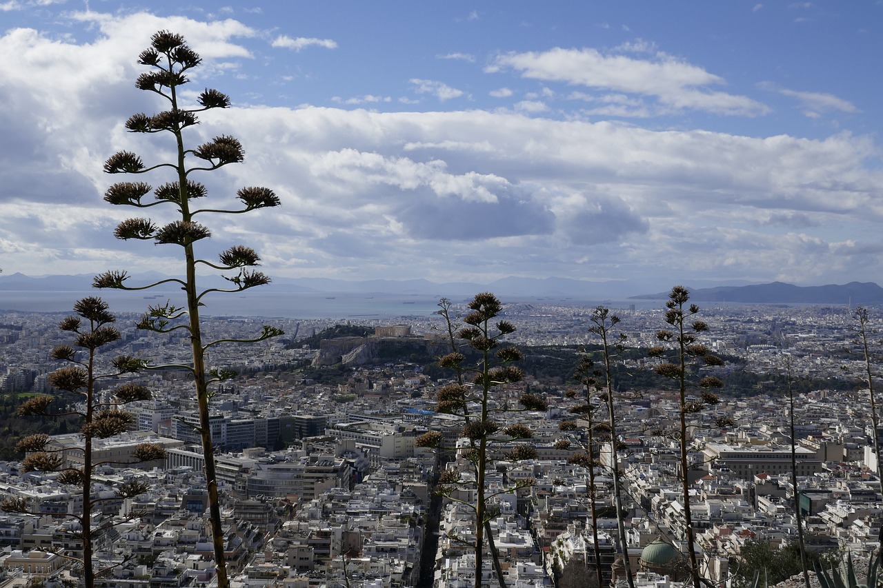 Vista di Atene in estate, con temperature elevate e turisti affollati tra le rovine storiche.