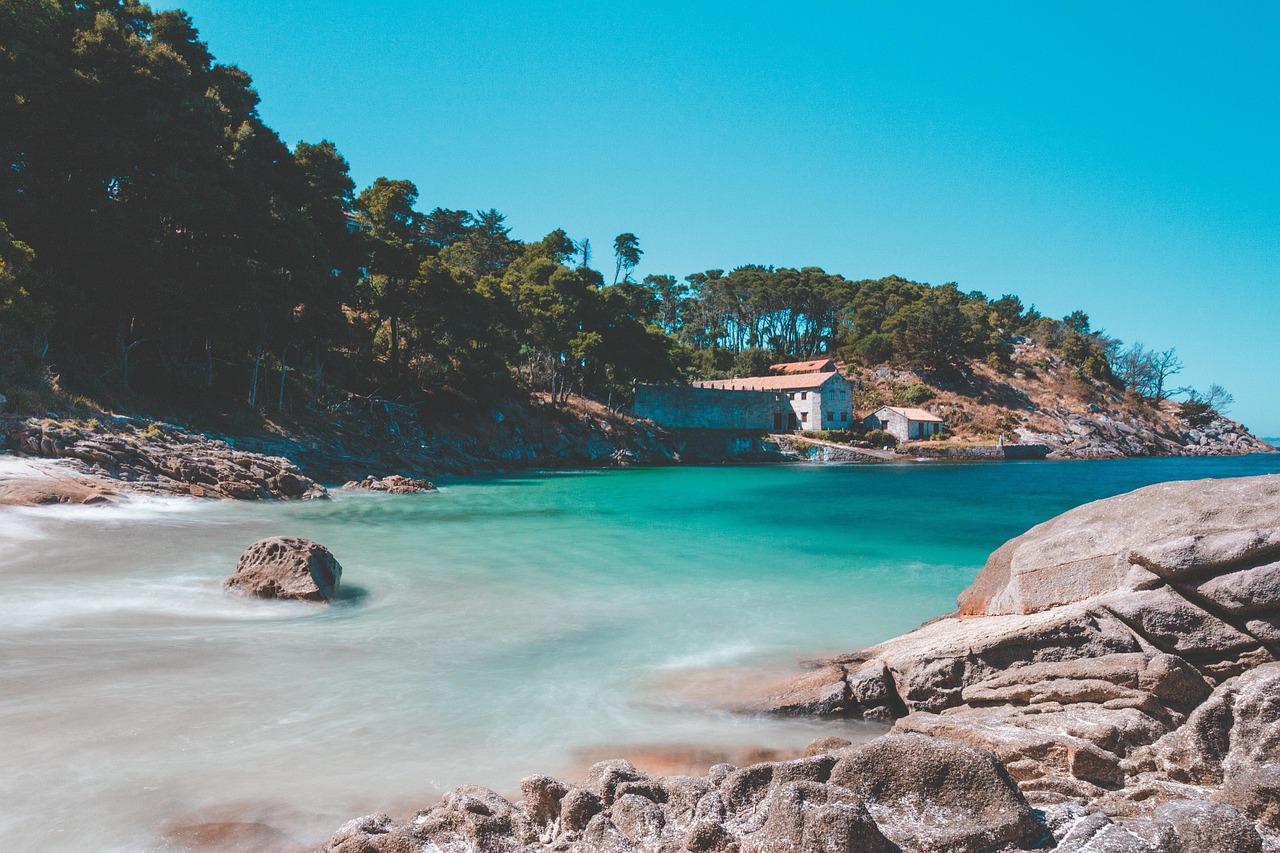 Spiaggia bagnata dal mare con scogliere e case colorate tipiche della costa francese.