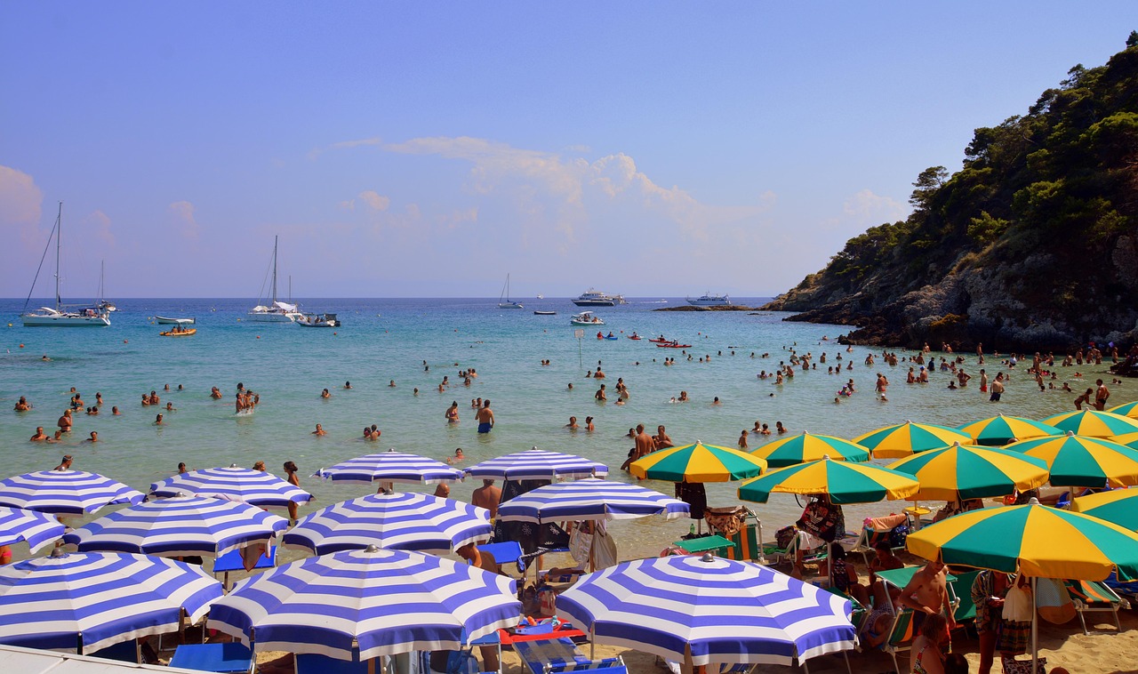 Spiaggia affollata in Sardegna, con bagnanti e ombrelloni sotto il sole.
