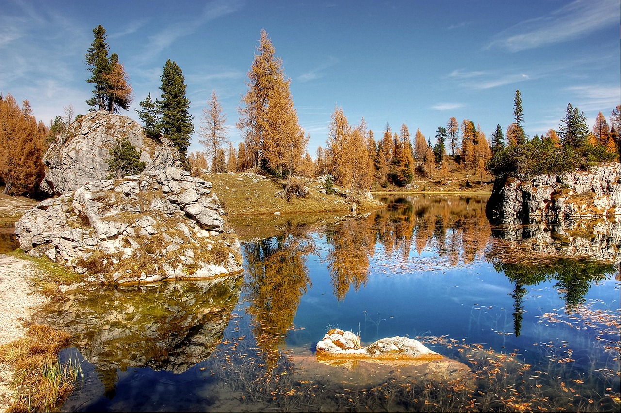 Lago veneto con riflessi autunnali, colori caldi e natura circostante.