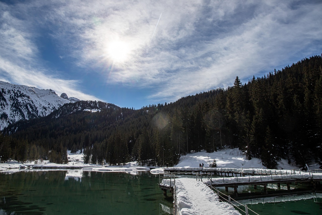 Lago di Braies circondato da montagne, riflessi sull'acqua cristallina in una giornata di sole.