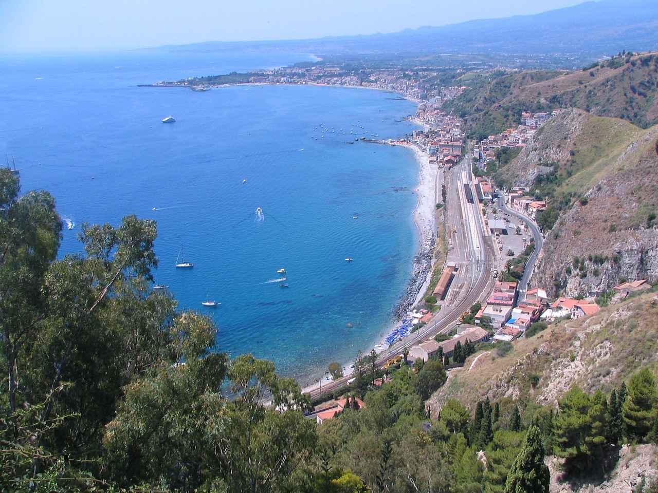 Vista panoramica di una spiaggia calabrese con acque cristalline e sabbia dorata.