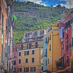 Villaggio ligure con case colorate e mercato del pesce fresco affollato da visitatori.