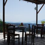 Trattoria rustica circondata da colline verdi, tavoli all'aperto e piatti tipici della tradizione.