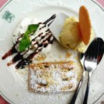 Immagine di un dolce tipico locale su un piatto, circondato da ingredienti freschi e tradizionali.