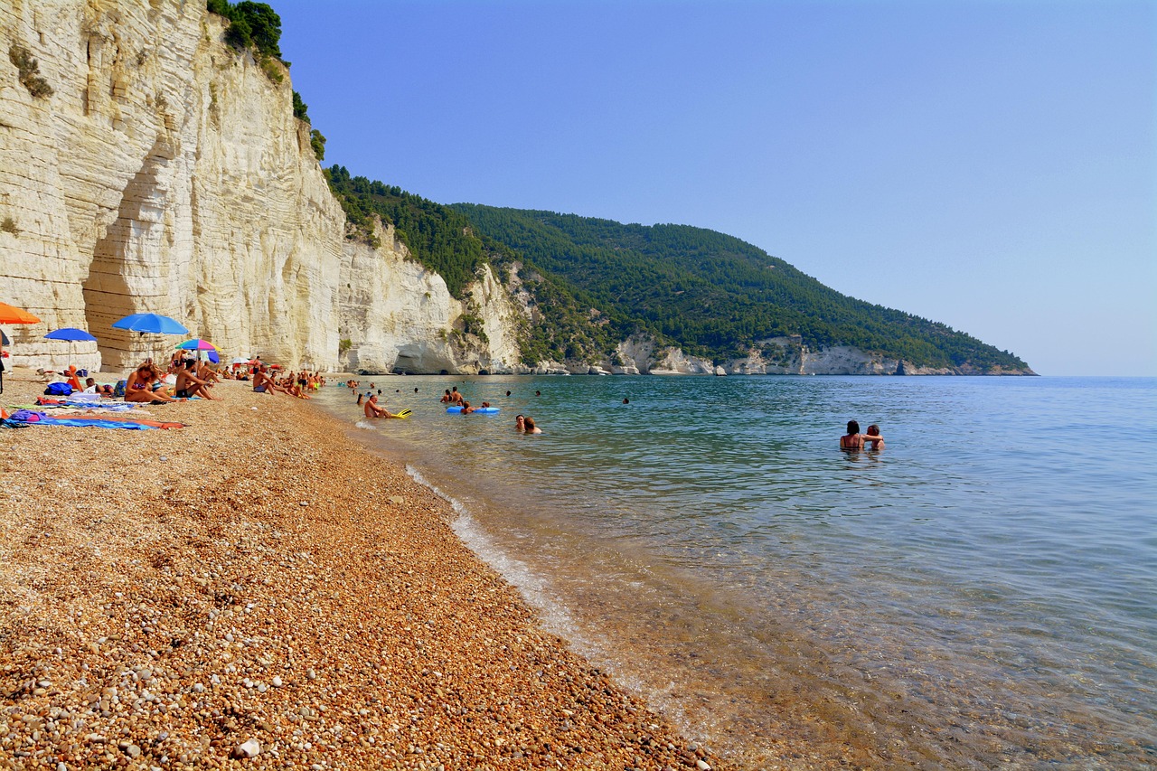 Spiaggia nascosta nelle Marche, con acque cristalline e scogliere verdi, meta perfetta per i turisti.
