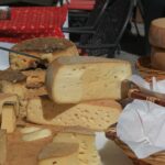 Paesaggio abruzzese con formaggi tipici e stand gastronomici durante un festival locale.