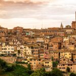 Borgo di Pitigliano al tramonto, con le sue storiche case di tufo illuminate da calde tonalità dorate.