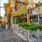 Piazza affollata con caffè storici e persone che gustano un espresso in una città umbra.