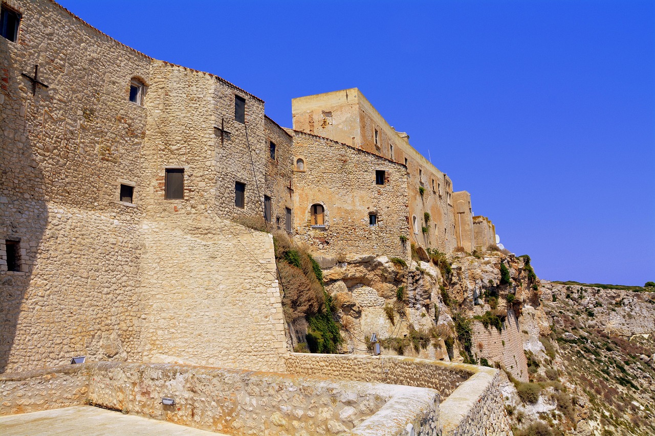 Vista panoramica del borgo di Castelsardo con la rocca e i cestini artigianali in primo piano.