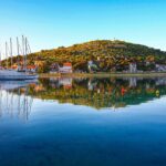 Vista panoramica di una pittoresca cittadina costiera croata con mare cristallino e architettura storica.