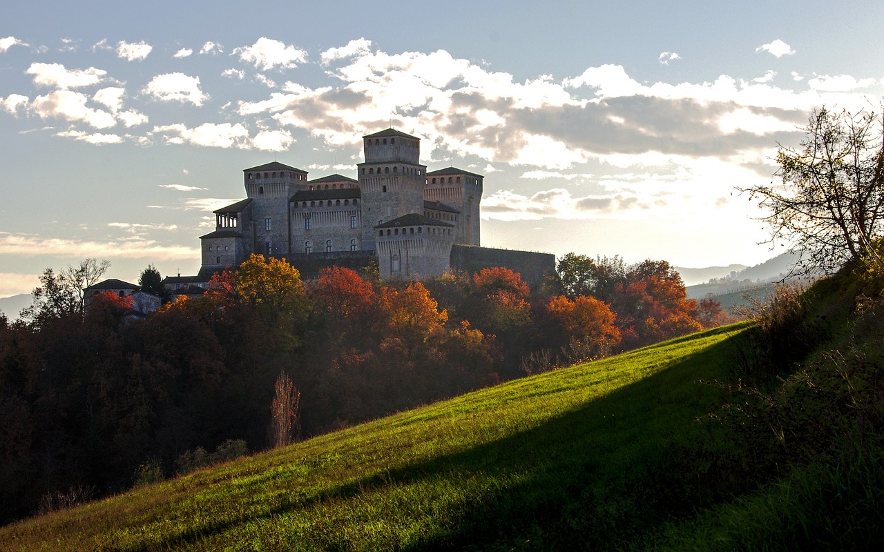 Castello piemontese con turisti in visita e degustazione di vino nel vigneto circostante.