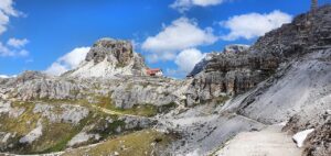Sentiero panoramico nelle Dolomiti verso una cascata nascosta tra le rocce e la vegetazione.