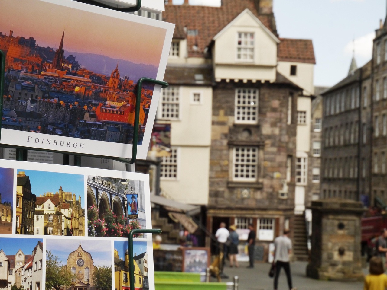 Vista panoramica di Edimburgo con il Castello sullo sfondo e turisti che esplorano la città.