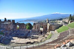 Panorama di un paese che evoca Catania, lontano dall'Etna, con architetture e paesaggi tipici.