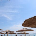 Panorama costiero dell'Albania con turisti, simbolo della crescita dei prezzi nel 2026.