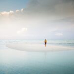Isola misteriosa visibile solo durante la bassa marea, con sentieri di sabbia e acqua circostante.