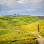 Panorama della località toscana più fotografata, con colline verdi e cipressi al tramonto.