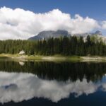 Lago alpino circondato da baite in un paesaggio montano della Svizzera italiana.