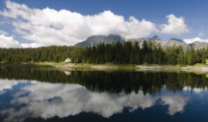 Lago alpino circondato da baite in un paesaggio montano della Svizzera italiana.