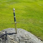 Immagine dell'abbazia senza tetto con la spada conficcata in una roccia al centro della scena.